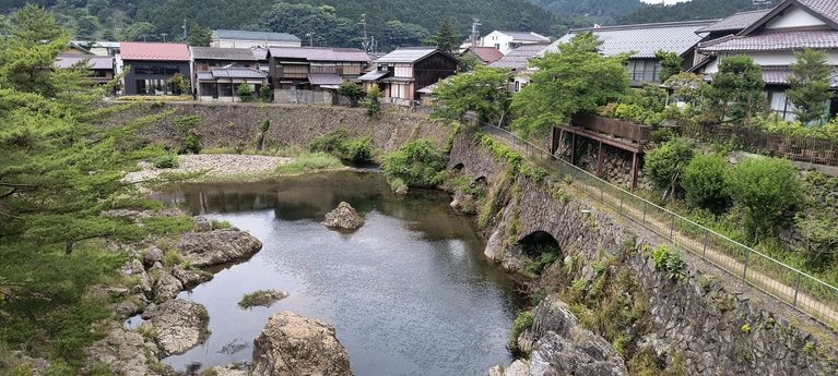 山あいの集落を流れる川と緑の山々